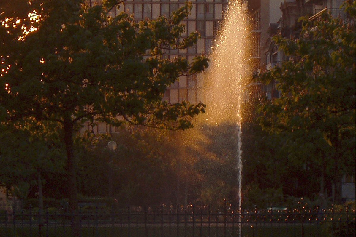 The rays of the setting sun lightens only half of the water jet, which rise up as a luminous dust.