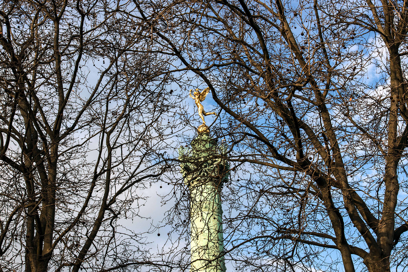 Nu au sommet de la colonne, le Génie de la Bastille, symbole de la Liberté, marche au milieu des arbres.